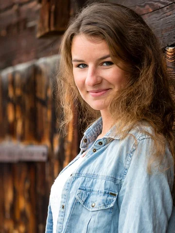Porträt einer jungen Frau vor einer dunklen Holzwand