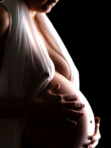 Schwangerschaftsporträt mit Händen sanft auf dem Bauch