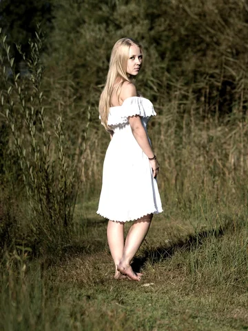 Porträt einer Frau im weissen Kleid in einer Sommerwiese