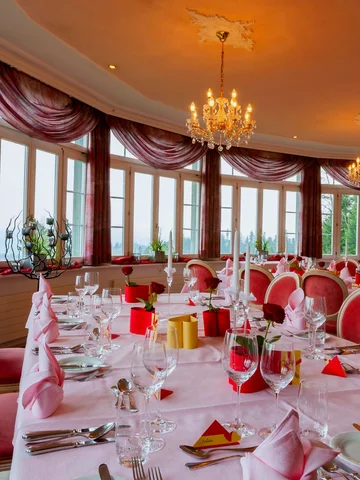 Festlich gedeckter Saal mit rosa Dekoration und Rosen